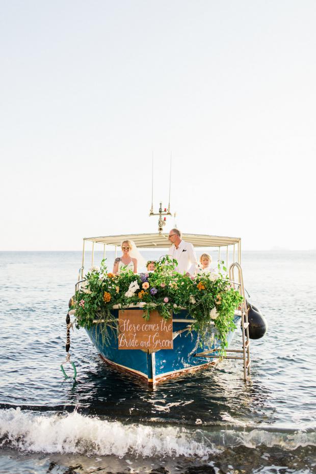 Beach wedding in Greece-Bride and groom arrive on a boat 